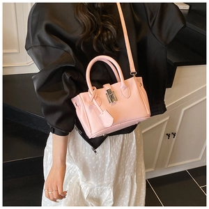 Detail shot of a pink bucket bag with leather texture and silver buckle on a model