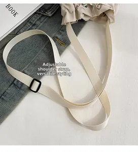 Detail view of the adjustable beige nylon shoulder strap with a matte black buckle