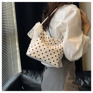 Dettaglio della borsa bianca a pois con fiocco in pizzo bianco sulla tracolla corta