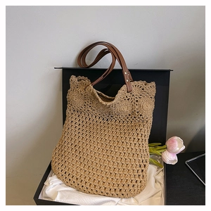 Detail of woven straw tote bag with scalloped edges and leather straps in a gift box