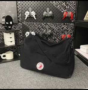 Close-up of black nylon tote bag with round embroidered logo and heavy-duty hardware