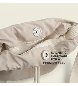 Detail view of silver magnetic snap closure on a beige drawstring bucket bag