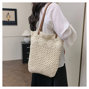 Detail of crochet floral pattern on a cream beach tote with brown leather strap