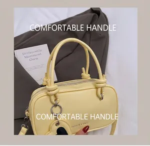 Détail du sac bandoulière jaune pâle avec anses rondes et fermeture éclair argentée