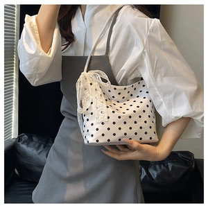 Dettaglio della borsa a spalla bianca a pois con un fiocco decorativo in pizzo fine