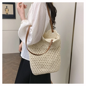Detailed close-up of handmade woven crochet shoulder bag with leather strap and metal rivets