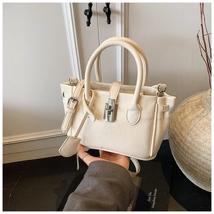 Macro detail of creamy white lychee grain leather handbag featuring a silver twist-lock closure