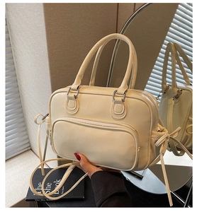 Detail of cream Boston bag with lychee texture and silver hardware in lifestyle setting