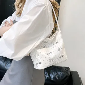 Dettaglio della borsa a spalla bianca a pois con pizzo e stampa sweet indossata dal modello