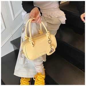 Vue détaillée du sac à main jaune pâle avec pendentif cœur et logo FASHION & BAGS