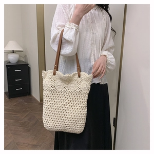 Detail of handwoven ivory hollow bucket bag featuring dark brown leather shoulder strap