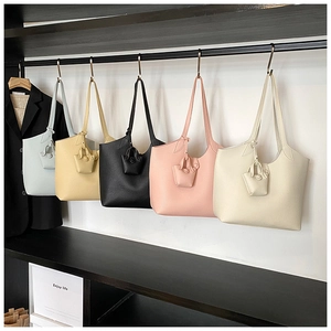 Row of colorful leather tote bags featuring matching mini pouch charms on a metal display