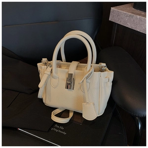 Detail of cream pebbled leather bucket bag with metal twist lock and dual handles