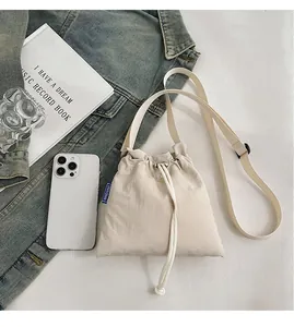 Beige drawstring nylon mini crossbody bag shown next to a smartphone for size scale