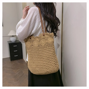 Detail of hand-woven shoulder bag with floral hollow patterns and faux leather strap
