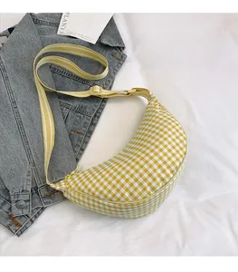 Detailed view of yellow gingham crescent bag with striped adjustable shoulder strap