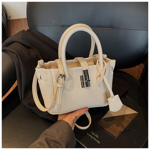 Detail of off-white lychee grain leather bucket bag with silver metal lock and top handles
