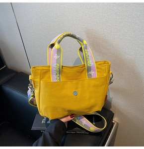 Detail der gelben Nylon-Tragetasche mit bunten Webgriffen und magnetischer Druckknopftasche