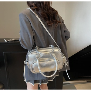 Side view of silver metallic leather Boston bag worn by model in a minimalist setting