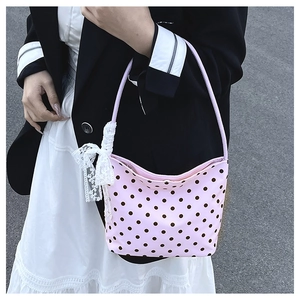 Borsa a spalla rosa a pois con fiocco in pizzo bianco mostrata in foto all'aperto