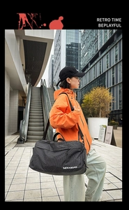 Détail d'un grand sac de voyage à carreaux noir avec bandoulière dans un cadre urbain