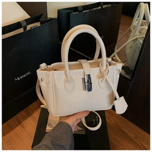 Detailed view of cream leather bucket bag featuring a silver twist lock and dual handles