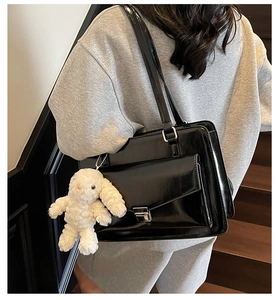 Détail du sac messager noir en simili cuir avec boucle argentée et breloque lapin blanc