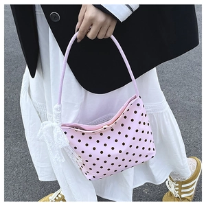 Dettaglio della borsa sottobraccio rosa a pois con un delicato fiocco di pizzo bianco sul lato