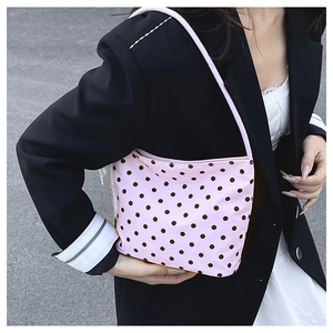 Borsa sottobraccio rosa a pois su modella in completo nero che mostra stile urbano