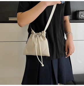Détail du sac à cordon en nylon blanc cassé avec bretelles en corde et étiquette bleue