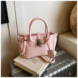 Detailed view of pink pebble leather handbag with silver clasp on vintage books