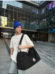 Versatile black nylon tote bag with wide shoulder strap in a modern urban sports style