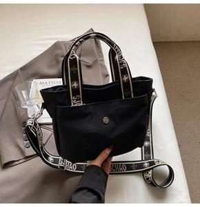 Detail der schwarzen Nylontasche mit Jacquard-Griff und breitem bedrucktem Schultergurt