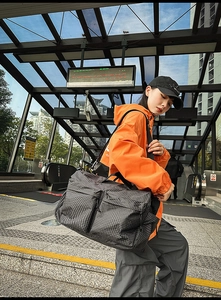 Détail du sac de voyage à carreaux gris avec large bandoulière en extérieur