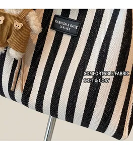 Détail d'un sac cabas en toile à rayures noires et blanches avec étiquette en cuir