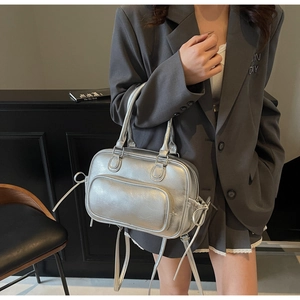 Silver metallic leather handbag with versatile straps shown in a minimalist urban setting