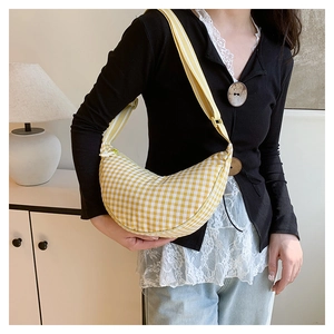 Detail of yellow and white checkered crescent bag with fabric texture and striped strap