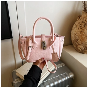 Close-up of pink lychee leather texture and silver twist lock on bucket handbag