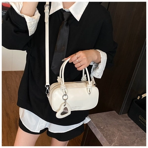 Détail du mini sac blanc avec poignée nouée, breloque miroir cœur et bandoulière réglable