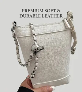 Gros plan du sac seau en cuir grainé blanc avec chaîne argentée et breloque boule