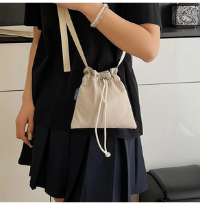 Detail of beige nylon crossbody bag with drawstring closure and blue NINGNING label