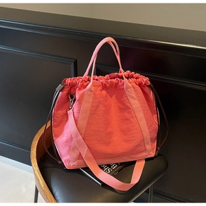 Roze nylon tote bag met trekkoord en verstelbare schouderband op een zwarte stoel