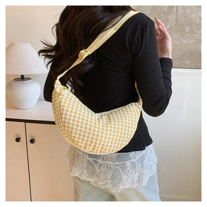 Detail of yellow and white checkered crescent crossbody bag worn with black outfit