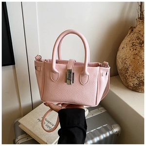 Detailed view of pink lychee grain leather bucket bag with silver metal lock and top handles