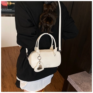 Sac Boston blanc avec poignées nouées et breloque cœur porté en bandoulière