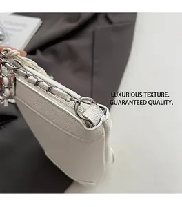 Détail du sac seau en cuir grainé blanc avec chaîne argentée et coutures de précision
