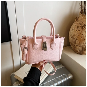 Close-up of pink lychee leather bucket bag with silver twist lock and adjustable strap