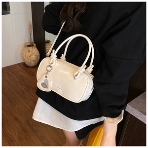 Vue détaillée du sac polochon crème avec logo de mode et pendentif en forme de cœur