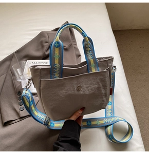 Detail eines breiten gewebten Gurtes mit Stickerei auf einer grauen Nylontasche