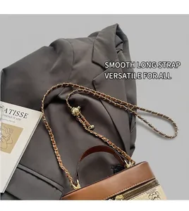 Detail of adjustable gold chain strap on two-tone bucket bag with cartoon bear motif